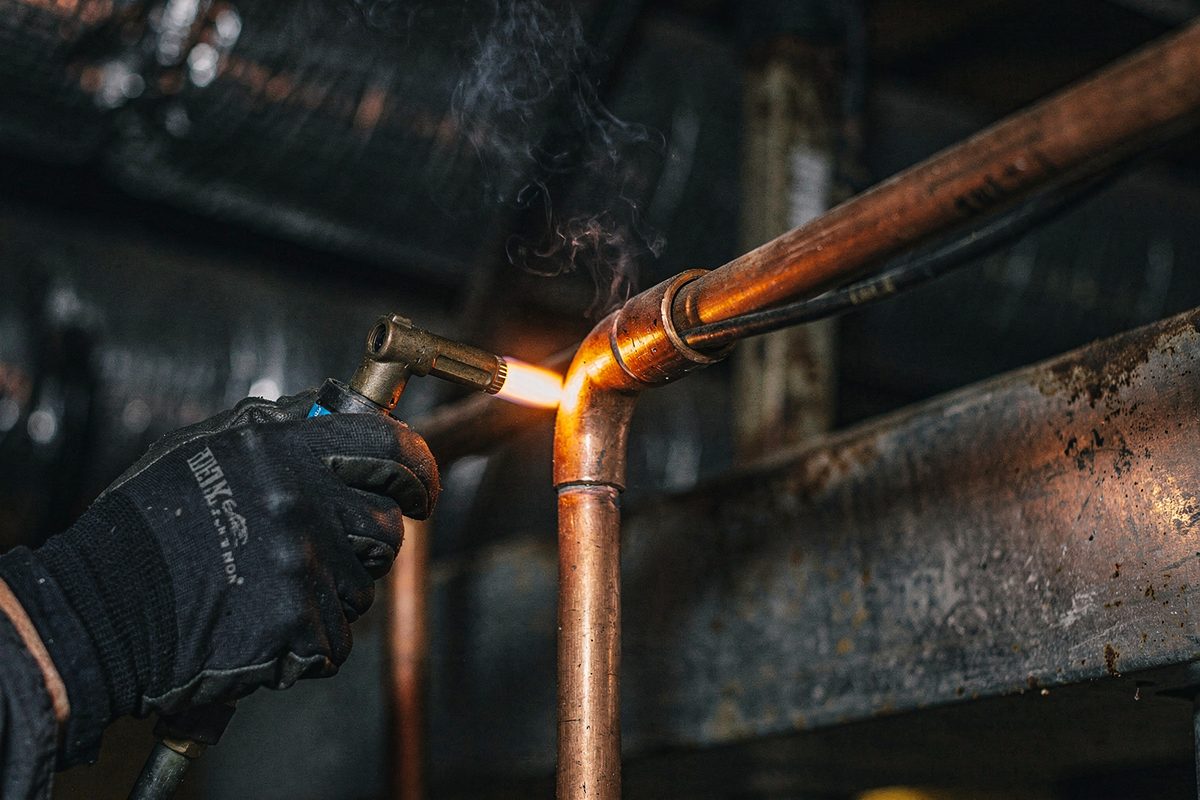 Technician brazing a copper refrigerant joint with a torch